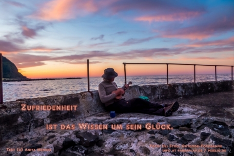Banjo-Spieler am Meeres-Ufer sitzend - Spruch: Zufriedenheit ist ...