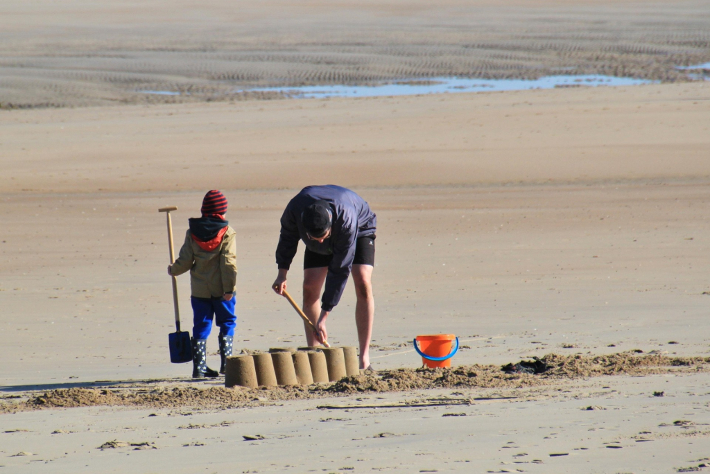 Vater mit Sohn am Strand beim Sandburgbauen